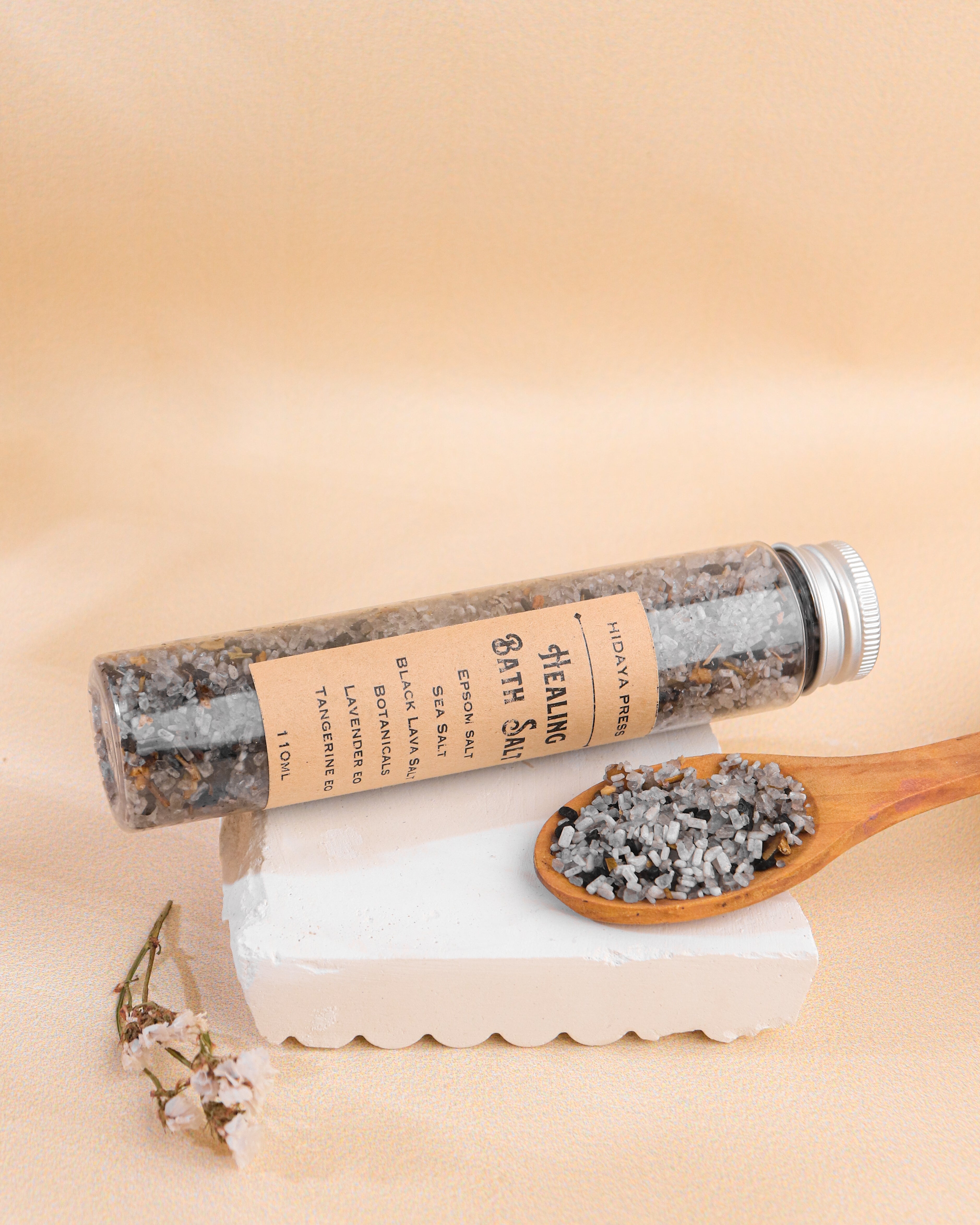 Bath salt tube with wooden spoon and stone on a beige background