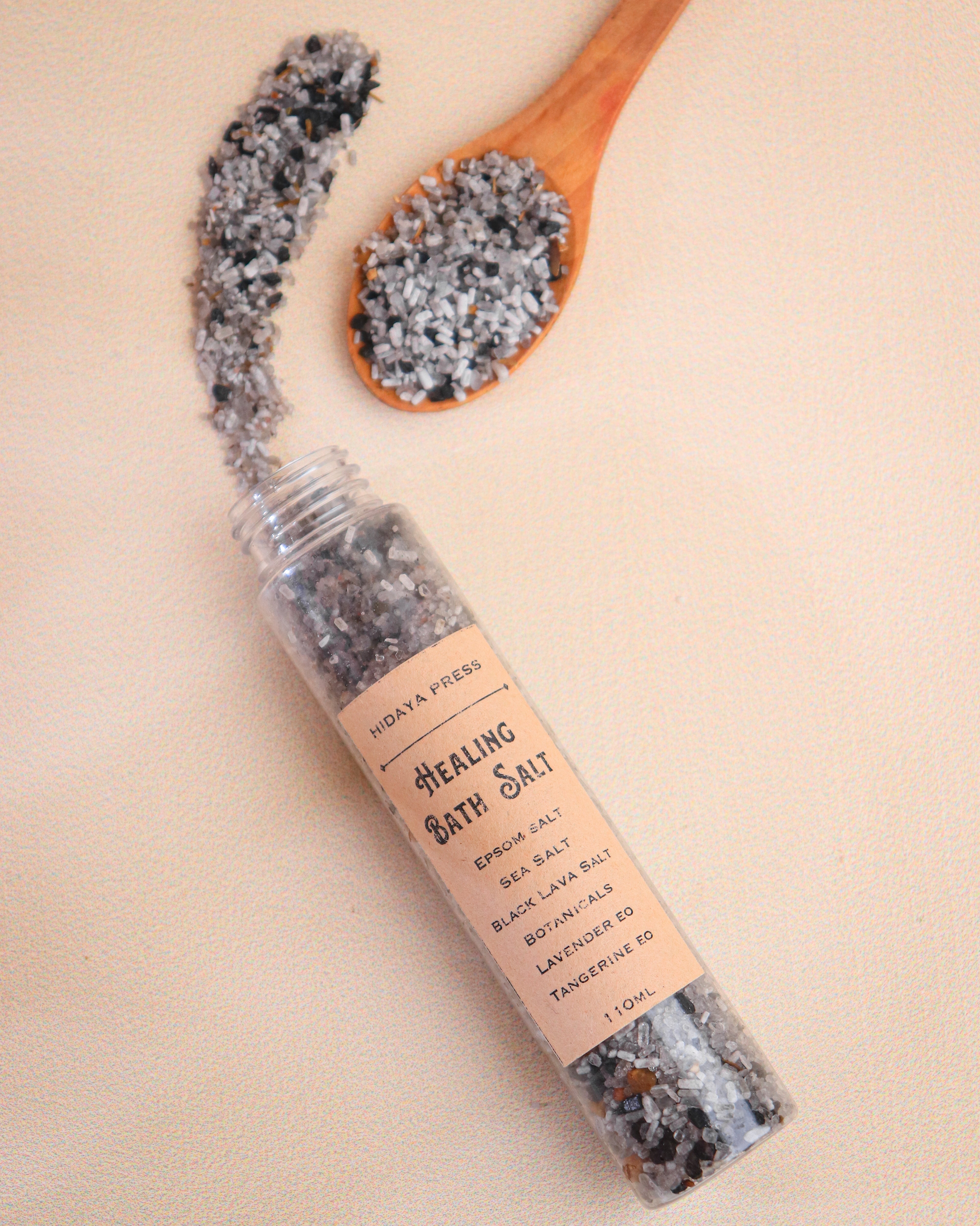 Healing bath salt in a glass tube with a wooden spoon on a beige background
