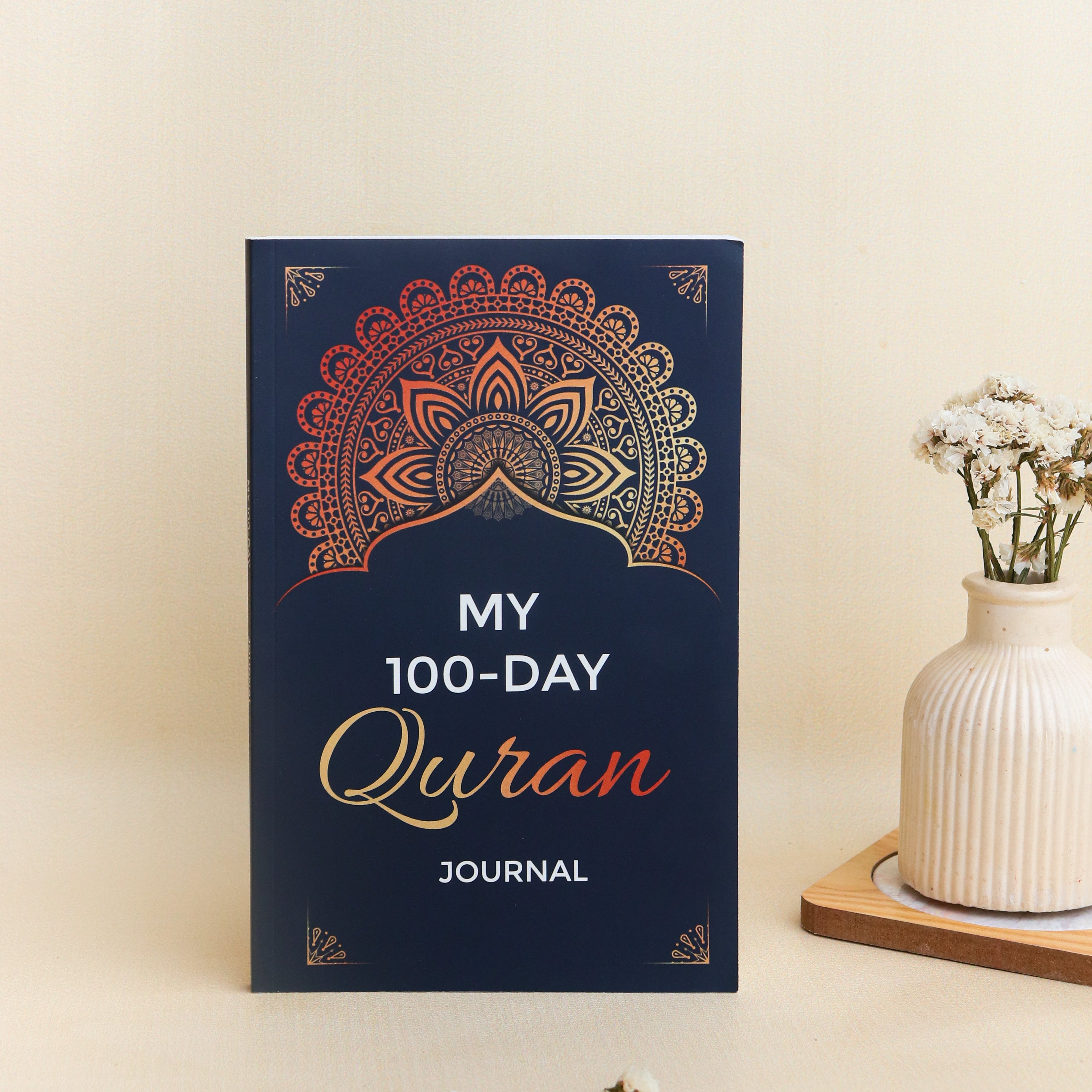 My 100-Day Quran Journal on a light beige background with a vase of flowers.