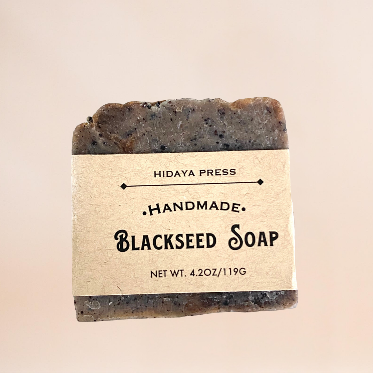 Handmade blackseed soap bar with a label on a beige background