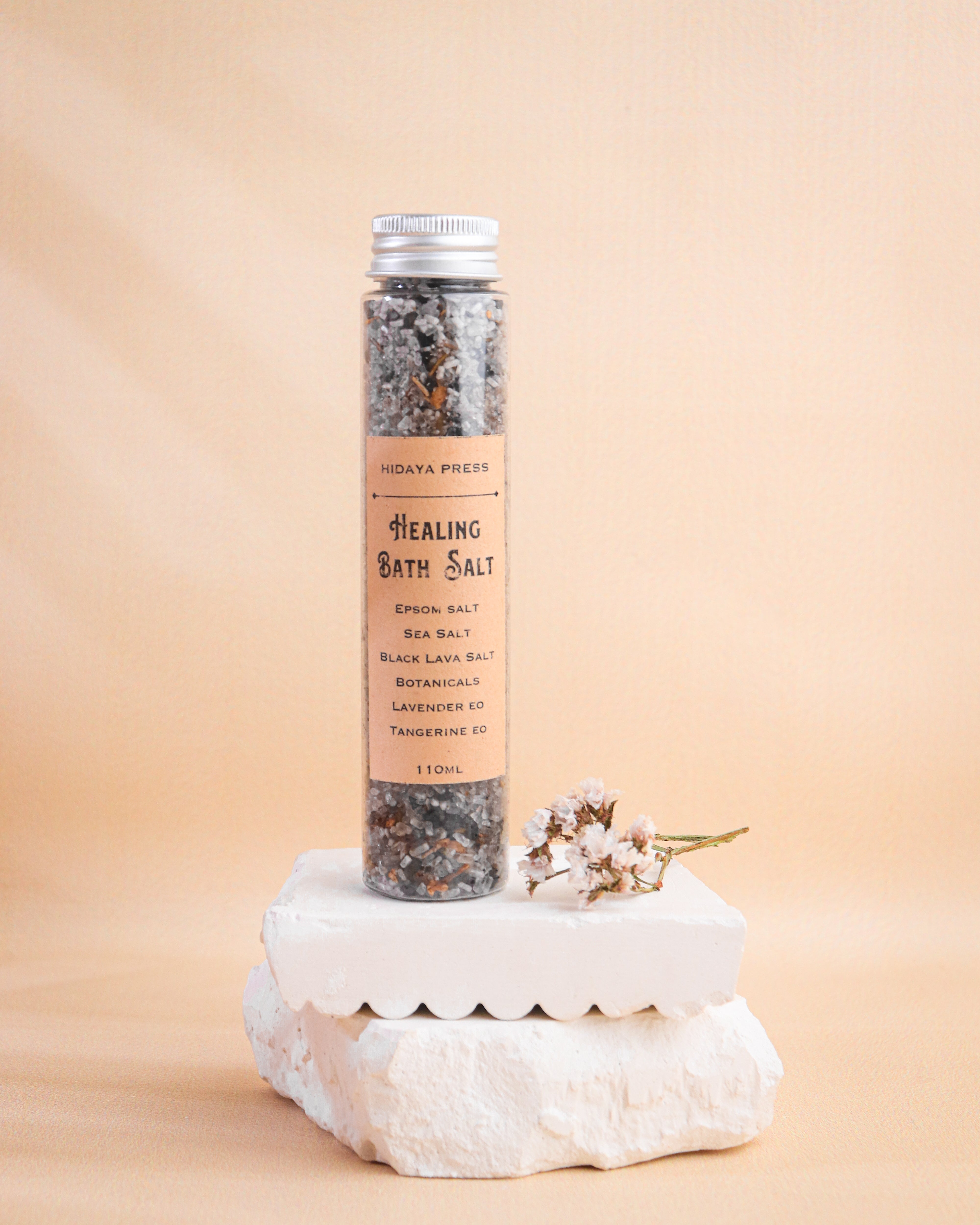 Healing bath salt bottle on a stone block with a beige background