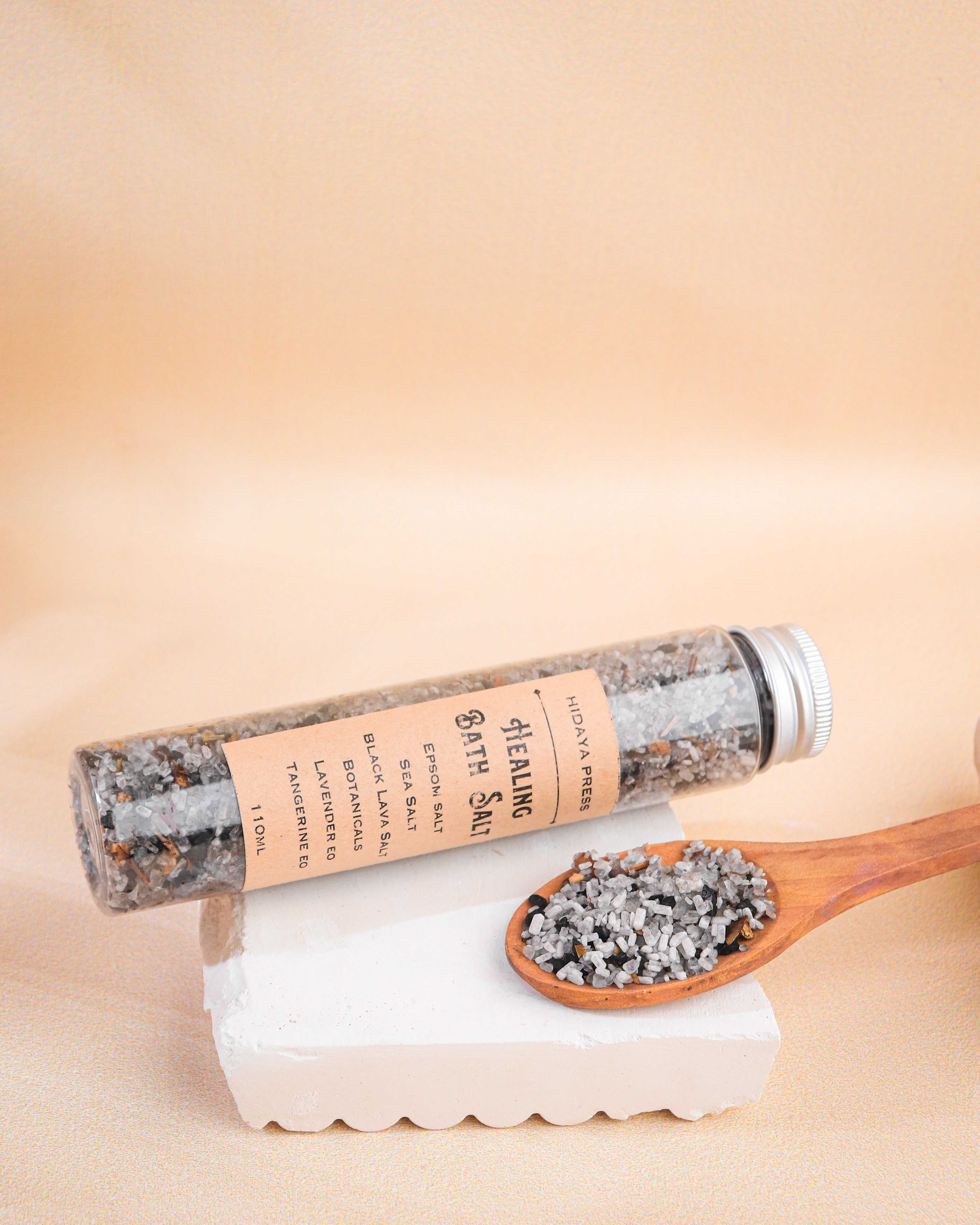 Bath salt tube with wooden spoon filled with salt on a beige background