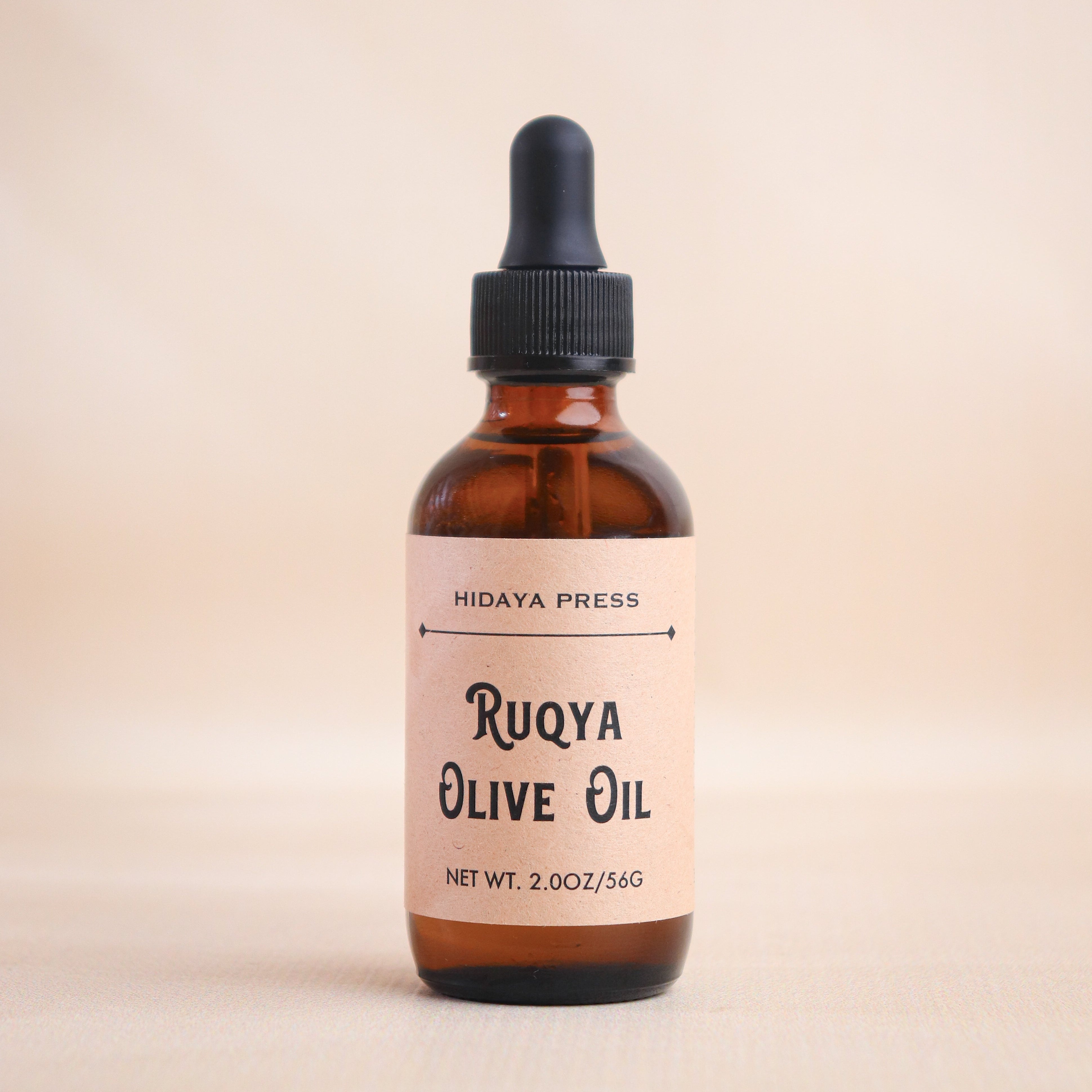Bottle of Ruqya Olive Oil with a dropper on a beige background