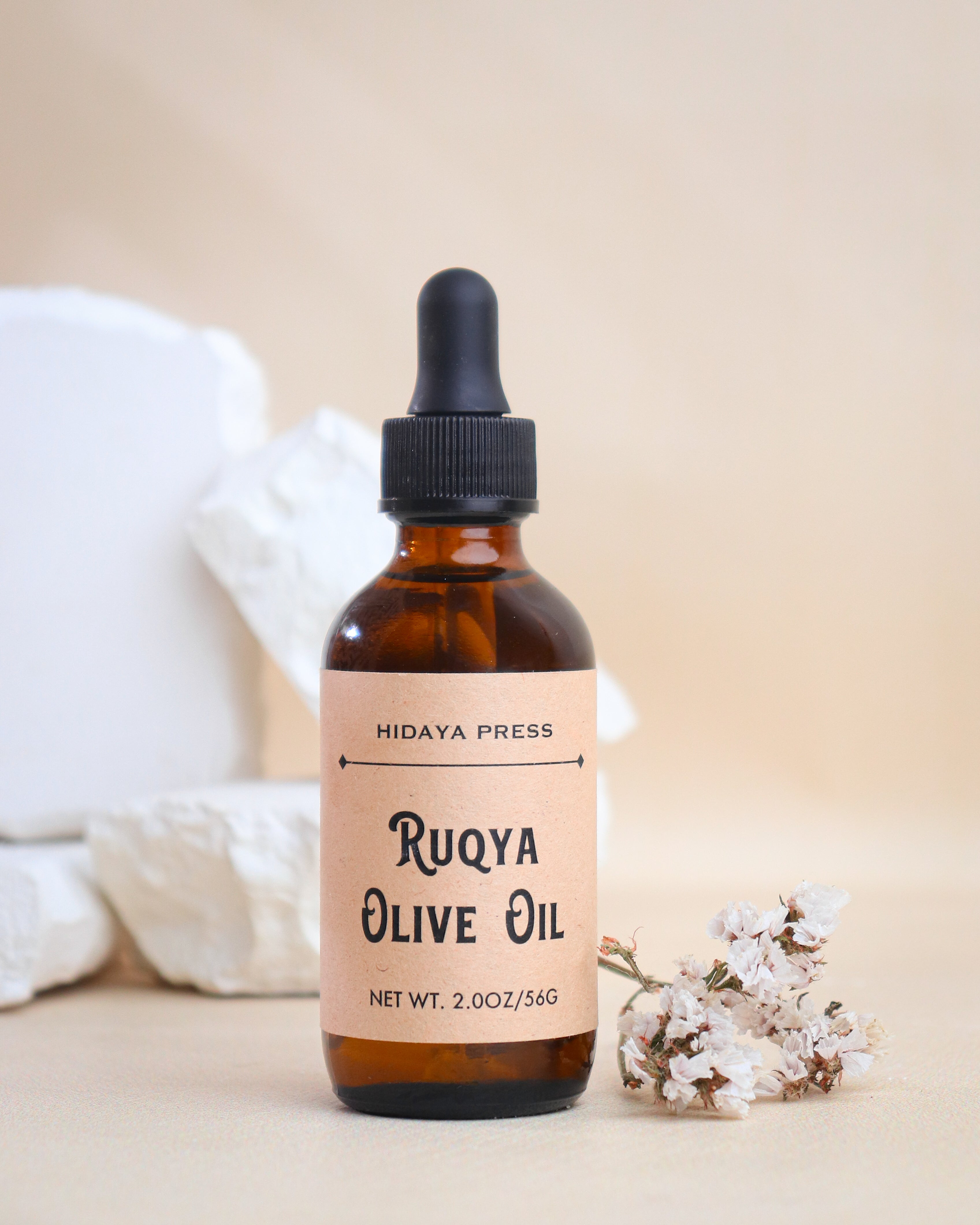 Bottle of Ruqya Olive Oil with a dropper on a beige background