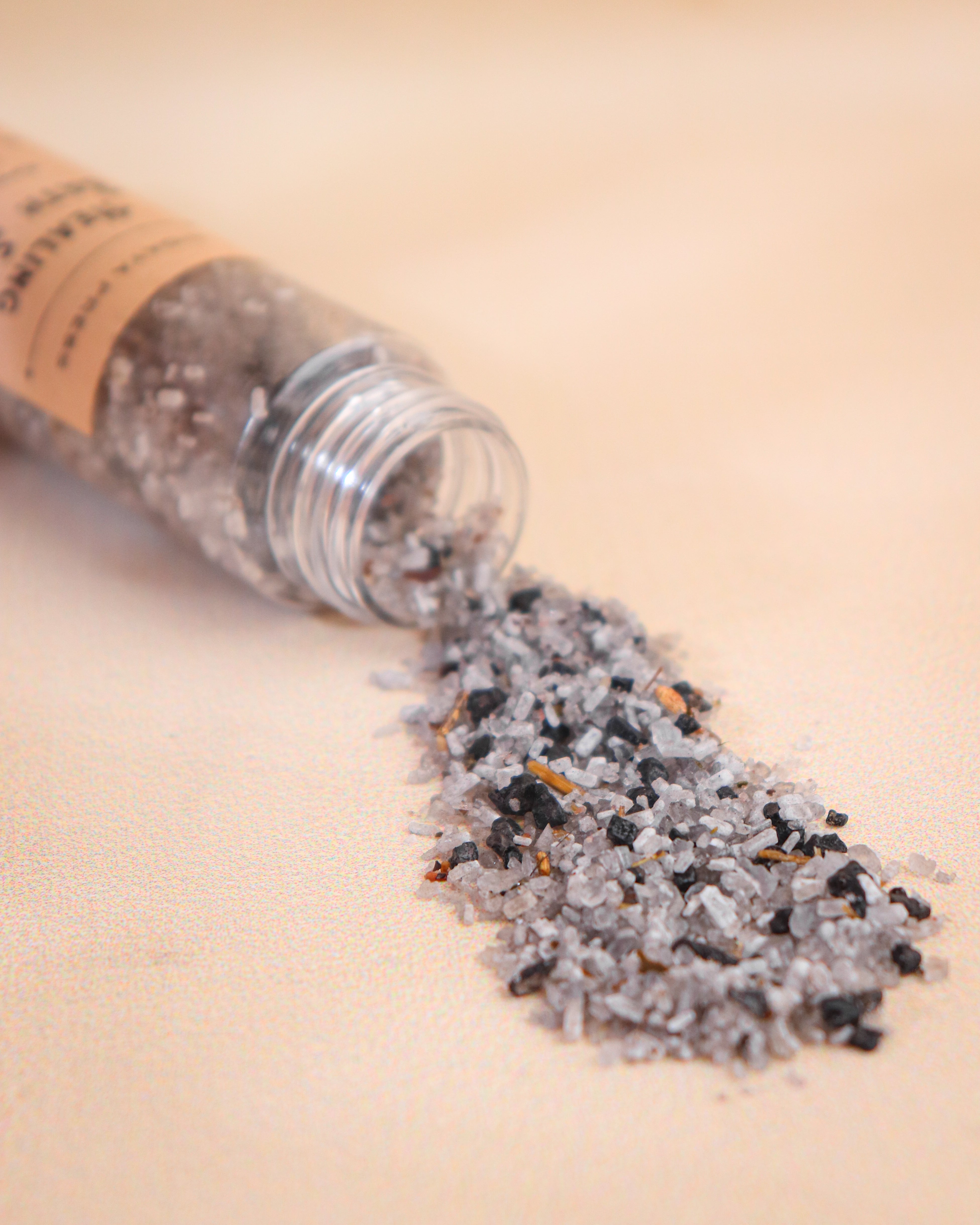 Healing bath salt with herbal salt spilling out on a beige surface